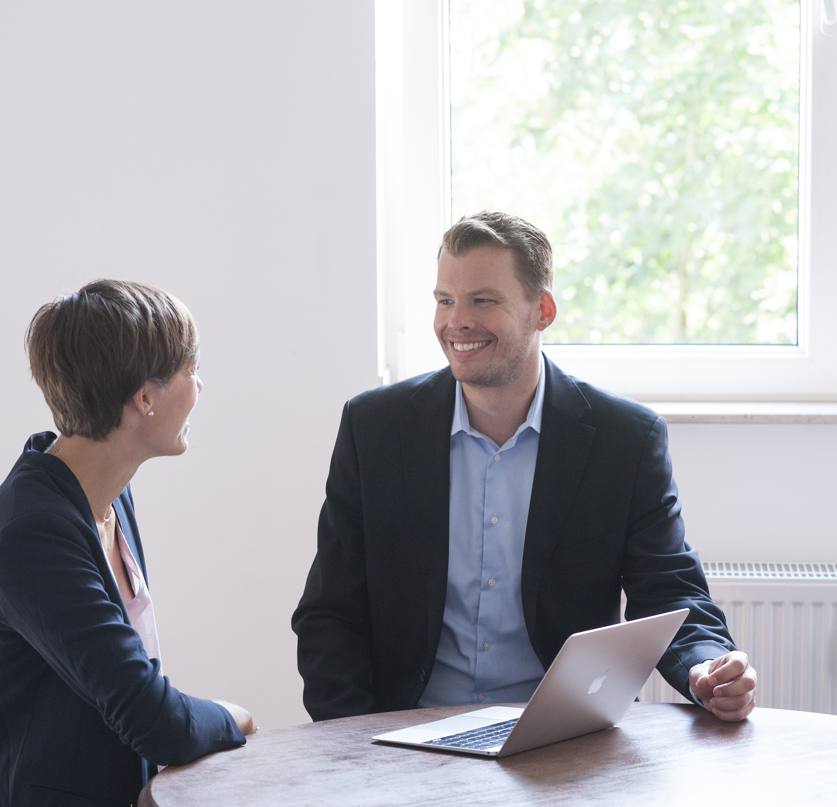 Two persons in conversion sitting at a table with a notebook